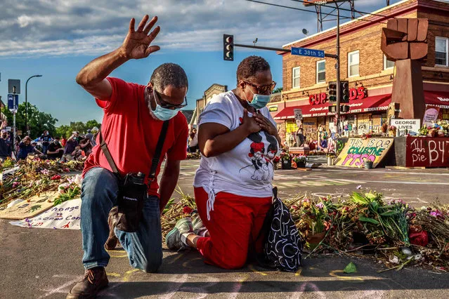 A couple kneels and raises their hands at a memorial for George Floyd following a day of demonstrations on June 13, 2020 in Minneapolis, Minnesota. Demonstrations are being held across the US following the death of George Floyd on May 25, 2020 in police custody. (Photo by Kerem Yucel/AFP Photo)