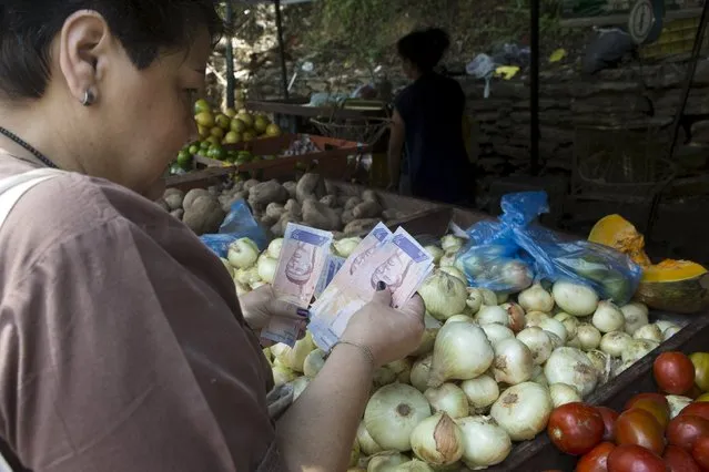 A woman counts bolivar notes as she pays for vegetables at a street market in Caracas, Venezuela, October 1, 2015. Venezuela's monthly inflation was 16.9 percent in September, the highest in a quarter-century, and has reached an annual rate of 179.5 percent, an opposition-leaning newspaper said on Thursday, citing a source close to the Central Bank. (Photo by Marco Bello/Reuters)