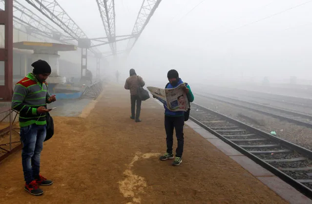 Passengers wait for their trains at a railway station amidst dense fog on a cold morning in Allahabad, India, January 5, 2018. (Photo by Jitendra Prakash/Reuters)