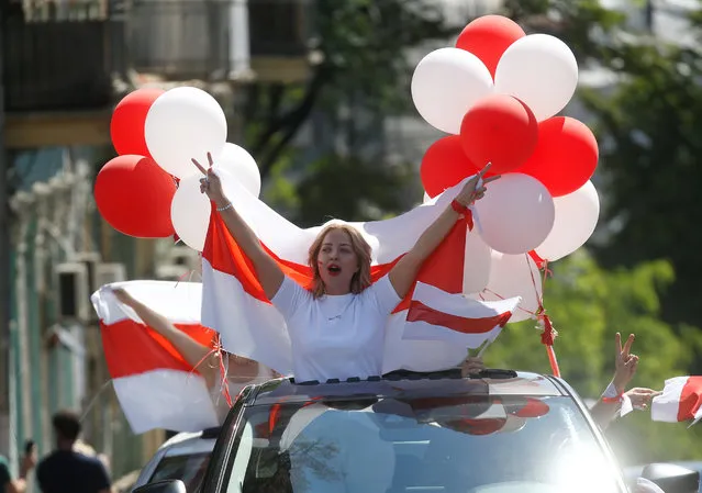 A woman holds a historical white-red-white flag of Belarus as she stands out of a car's sunroof during a rally in support of the Belarusian opposition, in central Kyiv, Ukraine on August 16, 2020. (Photo by Valentyn Ogirenko/Reuters)