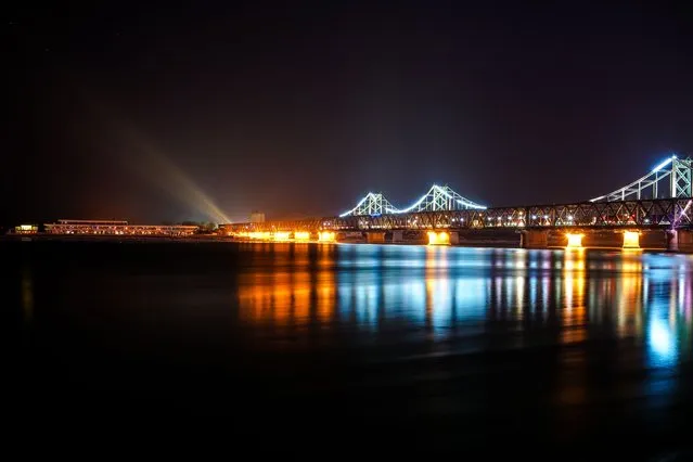 Spotlight beams (background C) are seen from the North Korean town of Sinuiju past Friendship Bridge and Broken Bridge as seen from Dandong, China's northeast Liaoning province, on January 10, 2018. (Photo by Chandan Khanna/AFP Photo)
