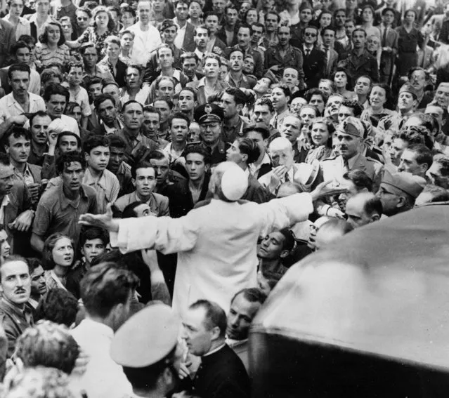 Men, women and soldiers gather around Pope Pius XII, his arms outstretched, on October 15, 1943, during his inspection tour of Rome, Italy, after the August 13 American air raid in World War II. (Photo by AP Photo)