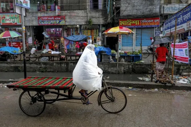 A Rickshawala cover-up with polythene save her from rain in Dhaka Bangladesh on August 27, 2020. (Photo by Kazi Salahuddin Razu/NurPhoto via Getty Images)