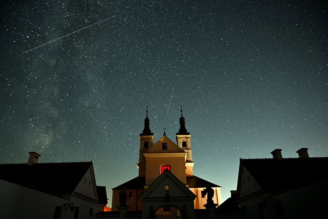 This long exposure picture shows a meteor (C) streaking as a satellite crosses the night sky over the Post-Camaldolese monastery in the village of Wigry, Suwalki region, during the annual Perseids meteor shower early on August 12, 2024. (Photo by Sergei Gapon/AFP Photo)