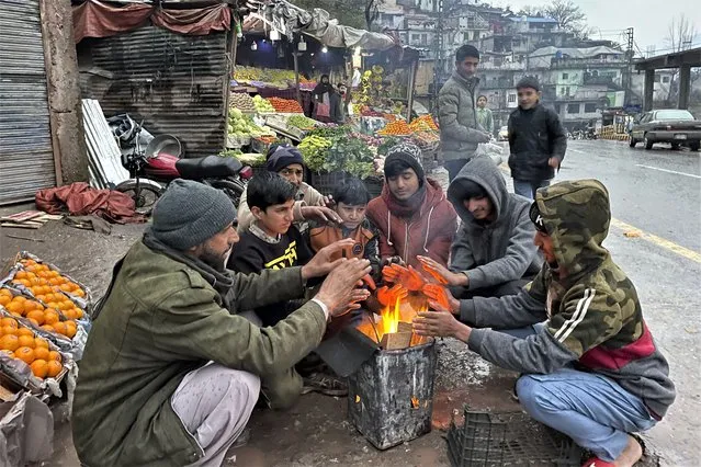 Vendors warm themselves as they light a bonfire at a market during a nationwide power outage, in Muzaffarabad on January 23, 2023. A massive power breakdown in Pakistan on January 23 affected most of the country's more than 220 million people, including in the mega cities of Karachi and Lahore. (Photo by Sajjad Qayyum/AFP Photo)