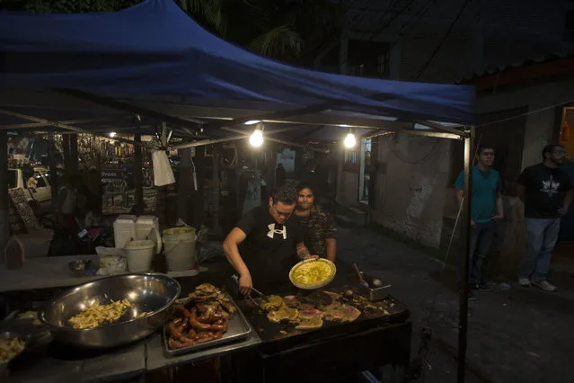 A couple sells roast meat near where anti-government demonstrators gather to protest at the Hato neighborhood in Tegucigalpa, Honduras, Friday, December 8, 2017. (Photo by Moises Castillo/AP Photo)