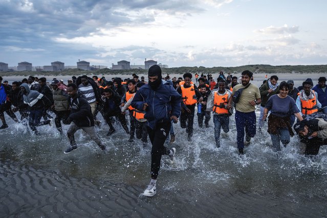 Migrant families wade into the sea in an attempt to board a small boat on August 12, 2025 in Gravelines, France. More than 50000 small boat migrants have now crossed the English Channel since Labour came to power last July. Last week the UK and France began implementing the so-called 'one-in, one-out' treaty, which was agreed during French President Emmanuel Macron's state visit last month, in an effort to curb illegal migration across the English Channel. Under the pilot scheme, a proportion of undocumented people arriving to the UK in small boats will be returned to France, in exchange for the same number of legitimate asylum seekers who may have family ties in the UK. (Photo by Dan Kitwood/Getty Images)