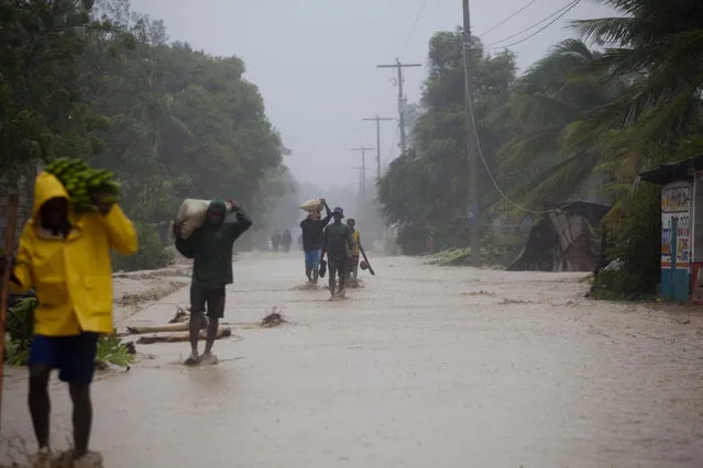Residents walk in flooded streets as they return to their homes in Leogane, Haiti, Tuesday, October 4, 2016. Matthew slammed into Haiti's southwestern tip with howling, 145 mph winds Tuesday, tearing off roofs in the poor and largely rural area, uprooting trees and leaving rivers bloated and choked with debris. (Photo by Dieu Nalio Chery/AP Photo)