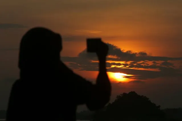 A local tourist takes a picture of the sun rise in Batam Island, Indonesia, 16 December 2017. Batam Island is an industrial area in Indonesia that is boosting the tourism sector to improve the economy of the community by exploiting the proximity of the region with nearby country Singapore. (Photo by Hotli Simanjuntak/EPA/EFE)