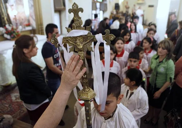 A worshipper reaches to touch a crucifix during Easter mass at Virgin Mary Chaldean Church in Baghdad, Iraq, Sunday, March 31, 2013. The Chaldean Church is an Eastern Rite church affiliated with the Roman Catholic Church. (Photo by Khalid Mohammed/AP Photo)