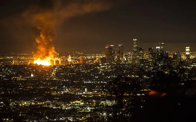 A large blaze at an apartment building under construction lights the sky near LA City Hall in downtown Los Angeles December 8, 2014. Fire destroyed a seven-story apartment building under construction in downtown Los Angeles and spread to a neighboring high-rise early Monday before flames were largely extinguished, forcing a major freeway shutdown through rush hour. (Photo by Eric Politzer/Reuters)