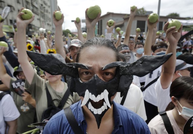 A supporter of opposition Taiwan People's Party (TPP) wears a devil mask as other supporters hold guavas, symbolizing dishonored ballots, during a march to protest against Lai Ching-te's ruling Democratic Progressive party, a day before his presidential inauguration in Taipei, Taiwan, Sunday, May 19, 2024. TPP demands that Lai''s government must implement parliamentary, judicial and constitutional reforms. (Photo by Chiang Ying-ying/AP Photo)