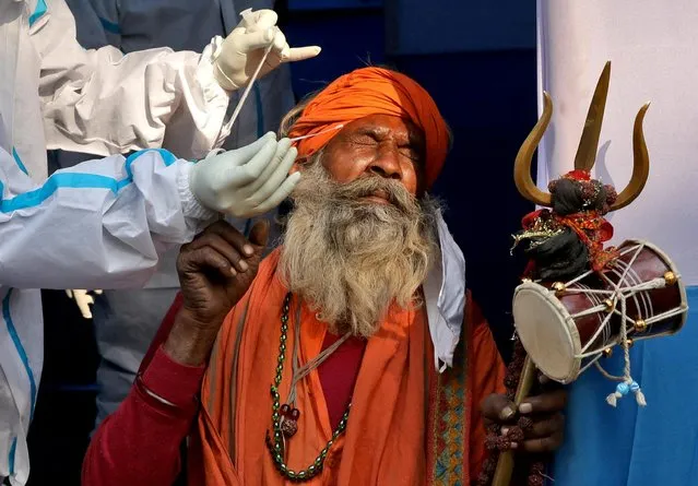 A Hindu holy man, or Sadhu, reacts as a healthcare worker collects a swab sample from him for a rapid antigen test at a base camp where pilgrims gather before heading for an annual trip to Sagar Island for the one-day festival of “Makar Sankranti”, amidst the spread of the COVID-19, in Kolkata, India on January 7, 2022. (Photo by Rupak De Chowdhuri/Reuters)
