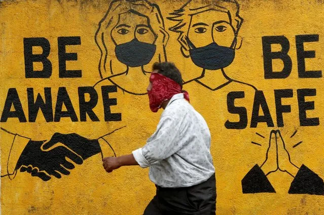 A man walks past a graffiti amid the spread of the coronavirus disease (COVID-19) in Mumbai, India, November 2, 2020. (Photo by Francis Mascarenhas/Reuters)