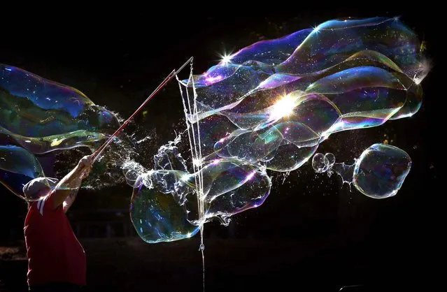 Paul Pedro, of Springfield, Ore., creates a flying cloud of soap bubbles at Skinner Butte Park in Eugene, Ore., Tuesday September 8, 2015. He was using custom sticks and ropes to make elaborate and ever changing bubble creations to the delight of visitors to the park. (Photo by Chris Pietsch/The Register-Guard via AP Photo)