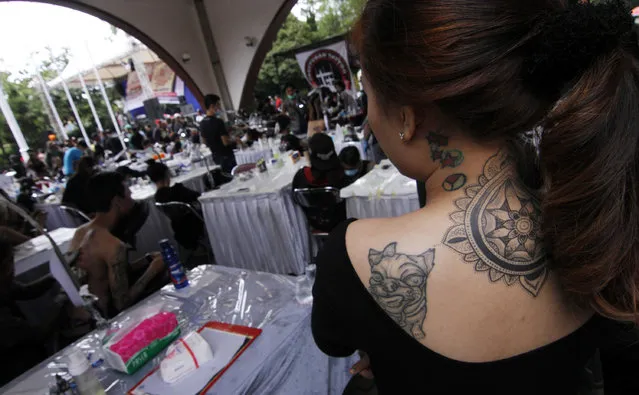 A woman looks on the tattoo making process during Bandung Body Art Festival at in Bandung, West Java, on December 7, 2014. (Photo by Rezza Estily/JG Photo)