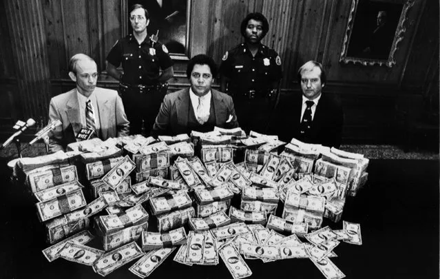 Atlanta Mayor Maynard Jackson, center, is flanked by security guards in his office as he poses with $100,000 reward money offered for clues to the deaths of 17 Atlanta children, February 21, 1981. (Photo by AP Photo)