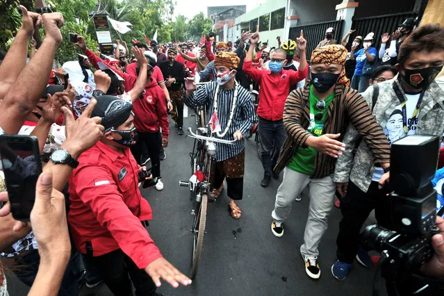 Gibran Rakabuming Raka (C), the son of Indonesia's President Joko Widodo, rides a bicycle to meet supporters after declaring victory in the mayoral election in Solo on December 9, 2020. (Photo by Anwar Mustafa/AFP Photo)