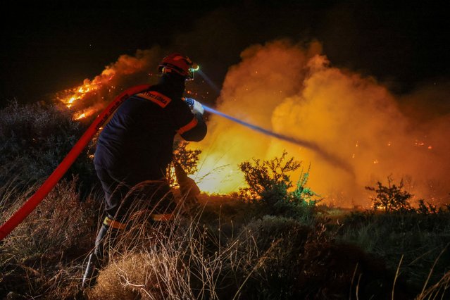 A firefighter tries to tackle a wildfire burning near the village of Petries on the island of Evia, Greece, on July 30, 2024. (Photo by Giorgos Moutafis/Reuters)