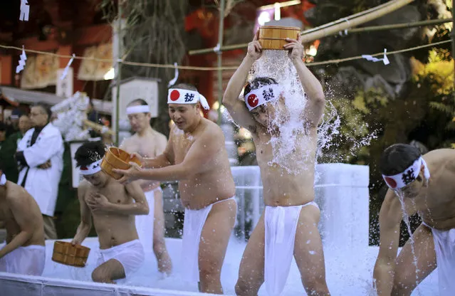 Half-naked shrine parishioners using a wooden tub pours cold water onto themselves during an annual cold-endurance festival at the Kanda Myojin Shinto shrine in Tokyo, Saturday, January 10, 2015. (Photo by Eugene Hoshiko/AP Photo)