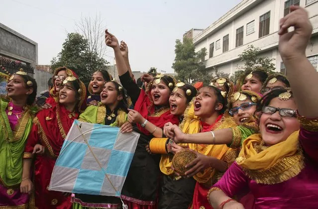 Schoolgirls wearing colourful dresses cheer as they fly a kite during the Lohri festival celebrations at their school in the northern Indian city of Amritsar January 12, 2015. Lohri marks the culmination of winter in many parts of northern India. (Photo by Munish Sharma/Reuters)