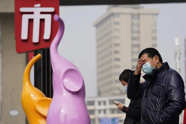 Residents wearing masks to curb the spread of the coronavirus stand near the Chinese character for “Market” in Wuhan, China, Tuesday, January 26, 2021. The central Chinese city of Wuhan, where the coronavirus was first detected has largely returned to normal but is on heightened alert against a resurgence as China battles outbreaks elsewhere in the country. (Photo by Ng Han Guan/AP Photo)