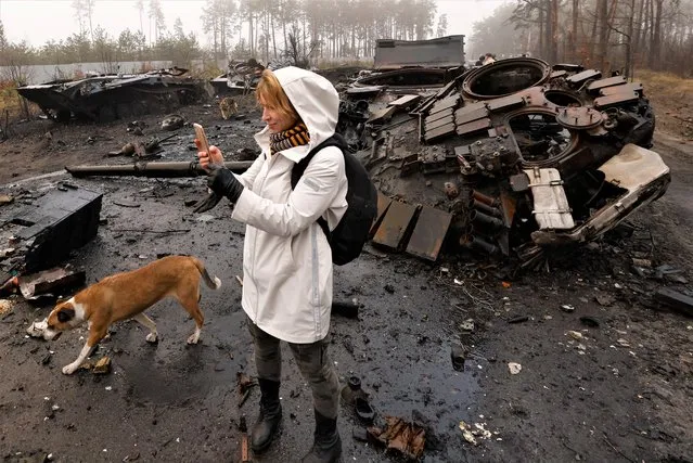 Iryna Vereshchagina, films with her mobile phone Russian destroyed tanks and armoured vehicles, amid Russia's invasion of Ukraine, in Dmytrivka village, west of Kyiv, Ukraine April 1, 2022. (Photo by Zohra Bensemra/Reuters)