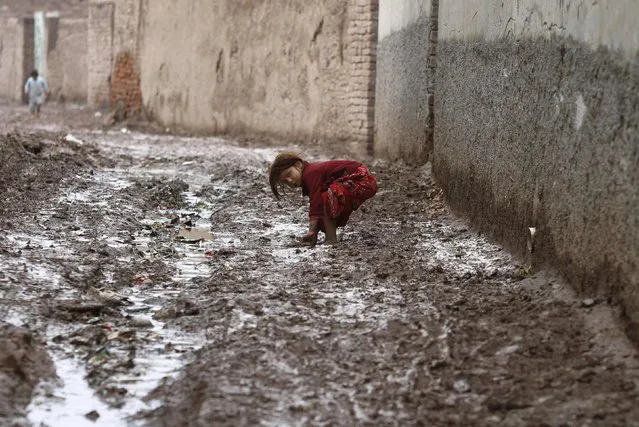 A girl reacts to camera as she bends to recover her pair of shoe from mud after the rain on outskirts of Peshawar January 22, 2015. (Photo by Fayaz Aziz/Reuters)