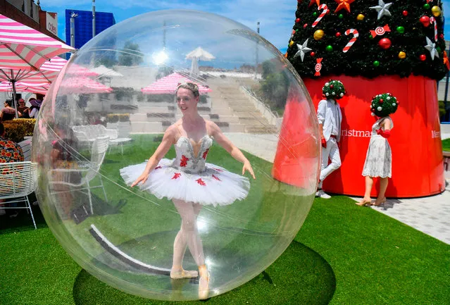 A ballet dancer poses in a giant plastic bubble as she entertains Christmas shoppers in Melbourne on December 13, 2020. (Photo by William West/AFP Photo)