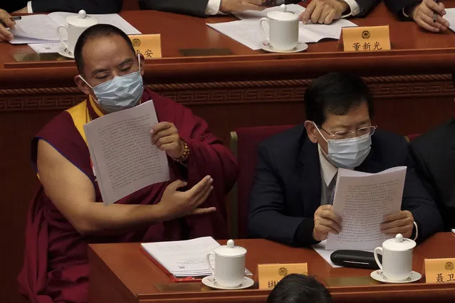 The 11th Panchen Lama Bainqen Erdini Qoigyijabu, left, a member of the National Committee of the Chinese People's Political Consultative Conference (CPPCC), left, wearing a face mask looks at a work reports during the opening session of the CPPCC at the Great Hall of the People in Beijing, Thursday, March 4, 2021. (Photo by Andy Wong/AP Photo)