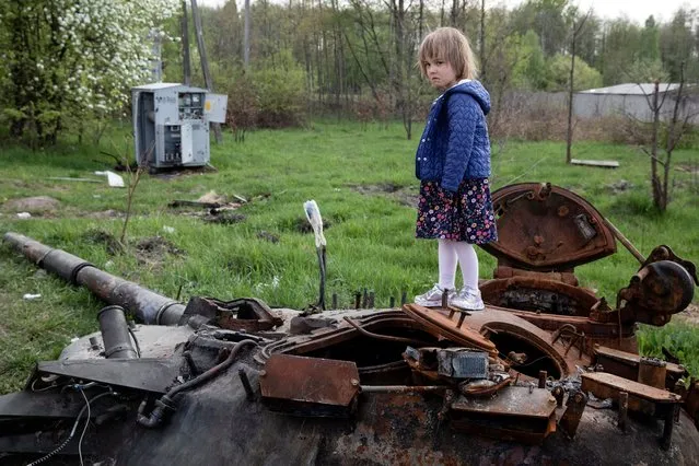 A child stands on a destroyed Russian tank, amid Russia's invasion of Ukraine, near Makariv, Kyiv region, Ukraine on May 7, 202. (Photo by Mikhail Palinchak/Reuters)