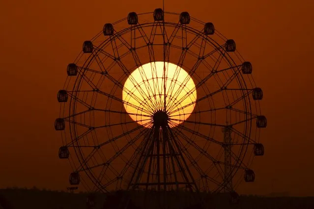 The sun is seen rising behind a skywheel in Korla, Xinjiang Uighur Autonomous Region, November 10, 2015. (Photo by Reuters/China Daily)