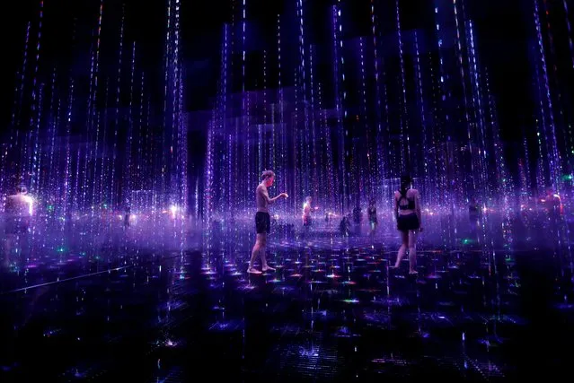Staffs of teamLab wearing swimming suits walk inside digital artwork combined with light, water and sound during a demonstration of TikTok teamLab Reconnect, digital artwork combined with sauna, ahead of its opening to the public this month in Tokyo, Japan, March 13, 2021. (Photo by Kim Kyung-Hoon/Reuters)