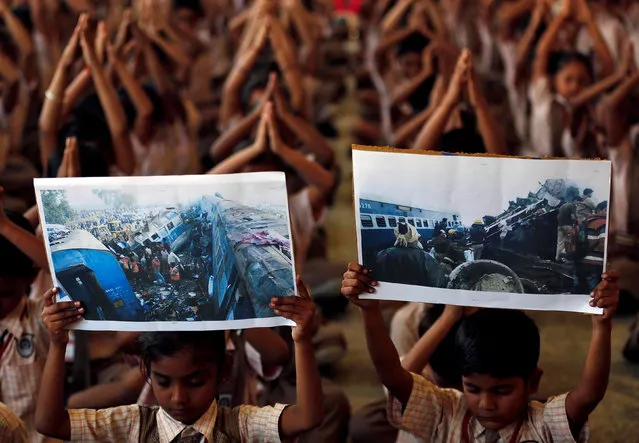 Children hold images showing Sunday's train accident at Pukhrayan, near Kanpur city, as they pray for the victims, at a school in Ahmedabad, India, November 21, 2016. (Photo by Amit Dave/Reuters)