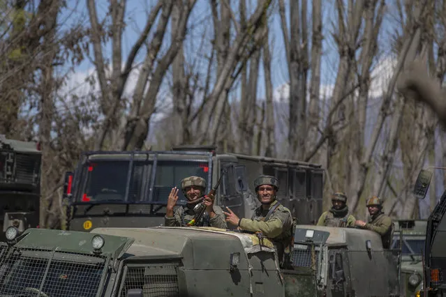 Indian army soldiers flash the victory sign as they leave the site of a gunbattle in Pulwama, south of Srinagar, Indian controlled Kashmir, Friday, April 2, 2021. Anti-India protests and clashes have erupted between government forces and locals who thronged a village in disputed Kashmir following a gunbattle that killed three suspected militants. Police say the gunfight on Friday erupted shortly after scores of counterinsurgency police and soldiers launched an operation based on tip about presence of militants in a village in southern Pulwama district. (Photo by Dar Yasin/AP Photo)