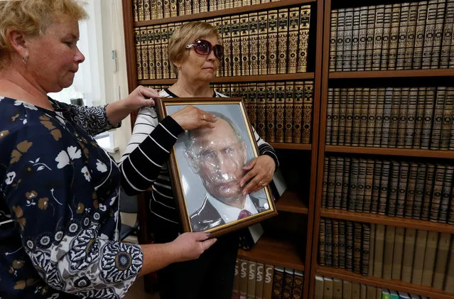 An employee helps a visitor to explore a tactile image representing the portrait of Russian President Vladimir Putin, at a specialized library for blind and partially sighted people in Krasnoyarsk, Russia September 11, 2018. (Photo by Ilya Naymushin/Reuters)