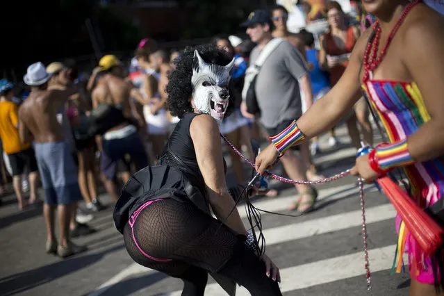 A reveler poses while wearing a wolf mask during the Banda de Ipanema carnival block party in Rio de Janeiro, Brazil, Saturday, February 14, 2015. The Banda de Ipanema is one of the largest block parties of Rio de Janeiro, and is celebrating it's 50th anniversary. (Photo by Silvia Izquierdo/AP Photo)