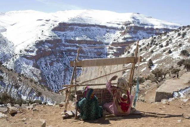 Berber women weave traditional carpets in the village of Ait Sghir in the High Atlas region of Morocco February 15, 2015. The snowy foothills of the High Atlas mountains in Morocco are home to several Berber villages where the inhabitants make their living by farming, baking bread in traditional ovens, herding cattle, and the making and selling of honey, olive oil and pottery. Extreme weather fluctuations and erosion that causes flooding and landslides have led to a drop in agricultural productivity, the United Nations said. (Photo by Youssef Boudlal/Reuters)