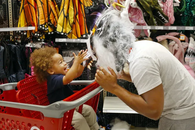 Liam Vasquez, 2, left and his father, Will Vasquez, right, try on Halloween masks at a Target department store on Wednesday, October 3, 2018, in Pembroke Pines, Fla. Discounters like Walmart and Target are expanding their costume offerings and creating designated sections where customers can find more of their Halloween needs in one place. (Photo by Brynn Anderson/AP Photo)