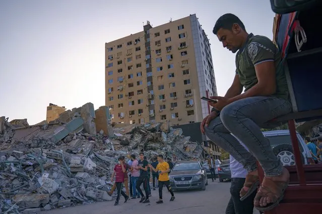 People gather to view the rubble of the al-Jalaa building following a cease-fire reached after an 11-day war between Gaza's Hamas rulers and Israel, in Gaza City, Friday, May 21, 2021. The building housed the Associated Press bureau in Gaza City for 15 years. (Photo by John Minchillo/AP Photo)