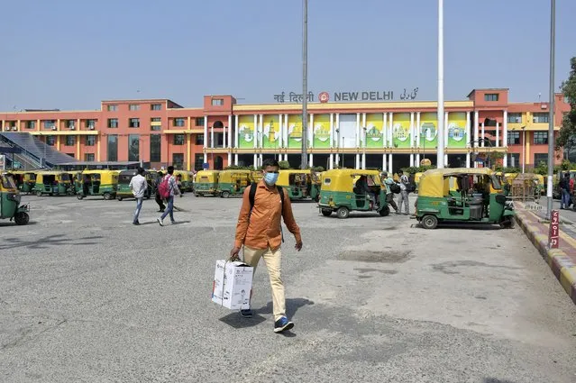 Passengers walk outside the New Delhi railway station in New Delhi, India, Monday, June 7, 2021. (Photo by Ishant Chauhan/AP Photo)