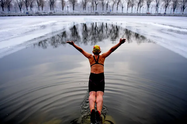 A woman jumps into a pool dug in the frozen river at Beiling Park in the smog on December 20, 2016 in Shenyang, Liaoning Province of China. Winter swimmers exercised in the smog in Shenyang. At least 24 cities in North China issued red alerts on Dec 16 as heavy smog will shroud the country's northern regions in the following days. (Photo by VCG/VCG via Getty Images)