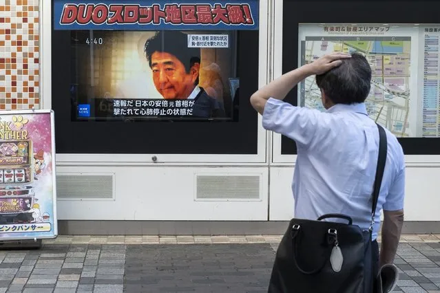 A man looks at a television broadcast showing news about the attack on former Japanese prime minister Shinzo Abe earlier in the day, along a street of Tokyo on July 8, 2022. Shinzo Abe was shot at a campaign event in the city of Nara on July 8, a government spokesman said, as local media reported the nation's longest-serving premier was showing no vital signs. (Photo by Charly Triballeau/AFP Photo)