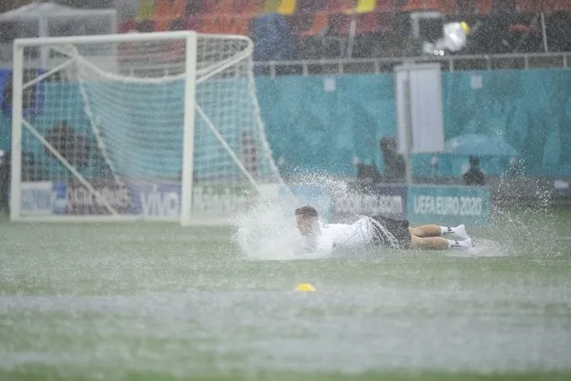 Austria's Christoph Baumgartner takes a dive on the pitch during a heavy rainfall before a training session at the National Arena stadium in Bucharest, Romania, Saturday, June 12, 2021, the day before the team's first match against North Macedonia. (Photo by Vadim Ghirda/AP Photo)