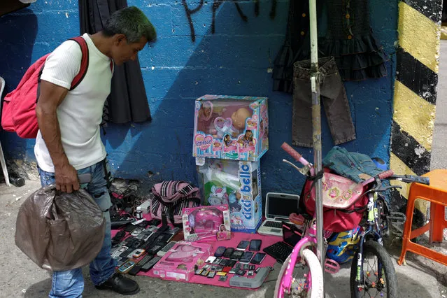 A man looks at second-hand toys at a street market in the slum of Catia in Caracas, Venezuela December 21, 2016. (Photo by Marco Bello/Reuters)