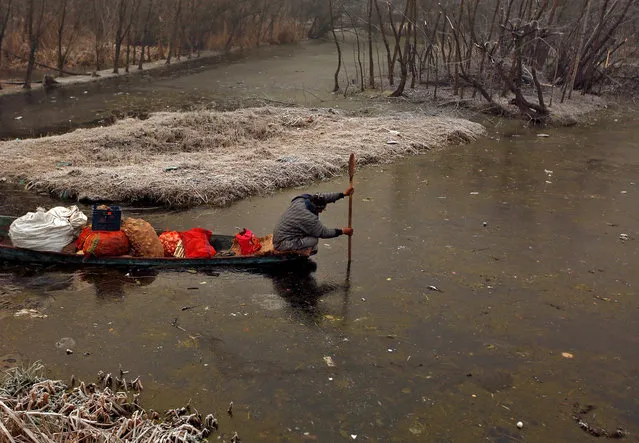 A man uses his oar to break ice to move his boat on the partially frozen interiors of Dal lake on a cold winter morning in Srinagar December 26, 2018. (Photo by Danish Ismail/Reuters)