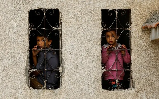 Palestinian children look out from a window with a grill at the site of Israeli strikes on houses, amid the ongoing conflict between Israel and Palestinian Islamist group Hamas, in Khan Younis in the southern Gaza Strip on November 9, 2023. (Photo by Ibraheem Abu Mustafa/Reuters)