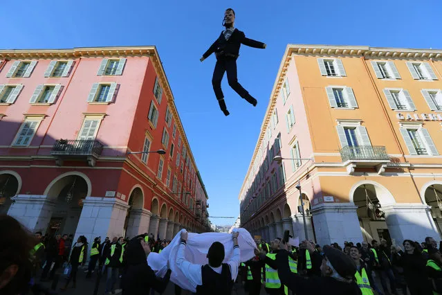 People toss with a sheet an effigy of French President Emmanuel Macron, a local carnival tradition, during an anti-government demonstration called by the Yellow Vests “Gilets Jaunes” movement, in Nice, southern France on January 12, 2019. (Photo by Valéry Hache/AFP Photo)