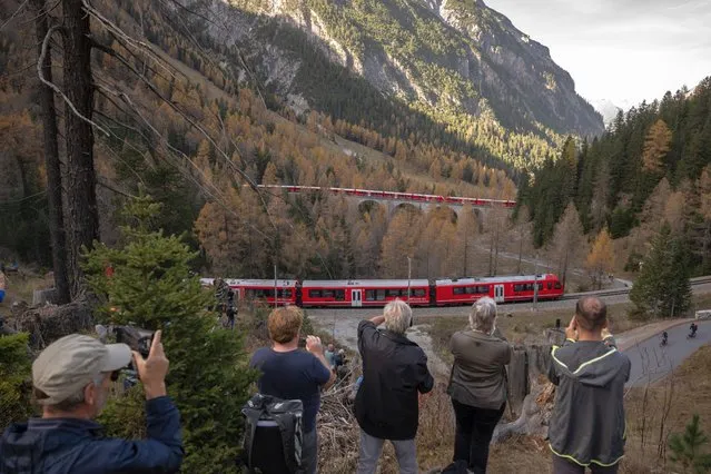 Members of the public capture images as a 1910-metre-long train with 100 cars passes near Bergun, on October 29, 2022, during a record attempt by the Rhaetian Railway (RhB) of the World's longest passenger train, to mark the Swiss railway operator's 175th anniversary. The record attempt is carried out on the Albula Line, from Preda to Thusis, crossing one of the most spectacular railways in the world, recognised as a Unesco World Heritage Site. (Photo by Fabrice Coffrini/AFP Photo)