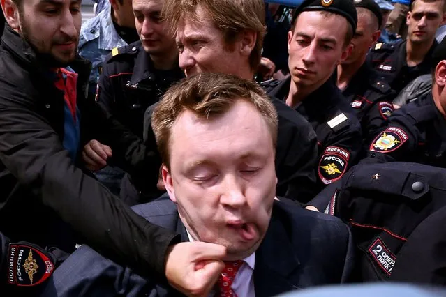 Unknown anti-gay activist hits Russia's gay and LGBT rights activist Nikolai Alexeyev (C) during unauthorized gay rights activists rally in cental Moscow on May 25, 2013. (Photo by Andrey Svitailo/AFP Photo)